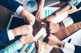 A professional atrium with two leather chairs, a geometric table and plant, and edison bulbs hanging from the ceiling.