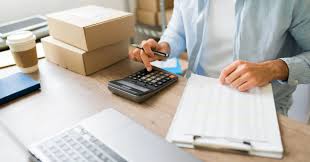 Two individuals sitting at a table, one writing on a clipboard, with a four different bottles of medication in the foreground.